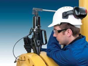 Field operator using the SWI2025TI step‑wedge flange spreader with integral pump to open a flanged joint.