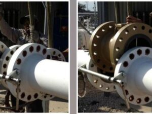 Mechanical valve removal tool spreading a flanged joint while operators remove the valve for maintenance.